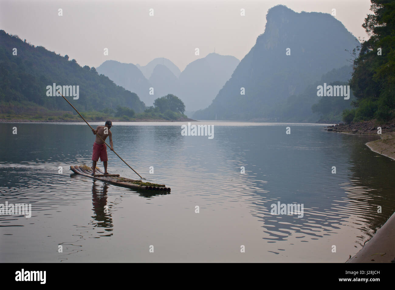 A man uses a traditional bamboo raft on a river in Yangshou, China ...