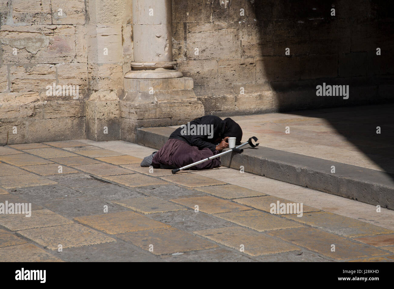 An old woman begging on the steps of Lisbon Cathedral, Portugal. Stock Photo