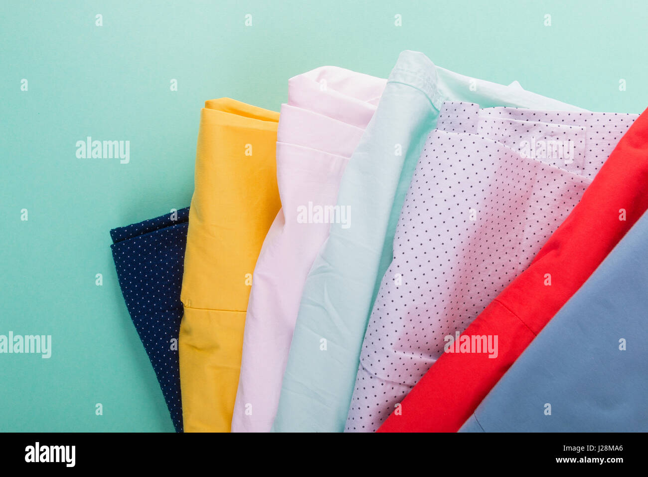 Stack of bright female trousers. Folded colorful pants and jeans. Close ...