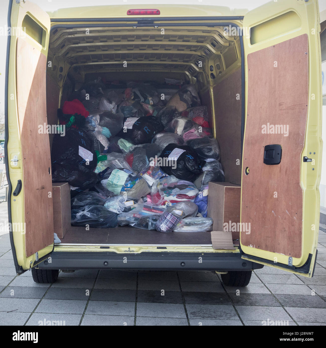 Marie Curie collection van full of plastic bags containing clothing outside Marie Curie charity shop. UK Stock Photo