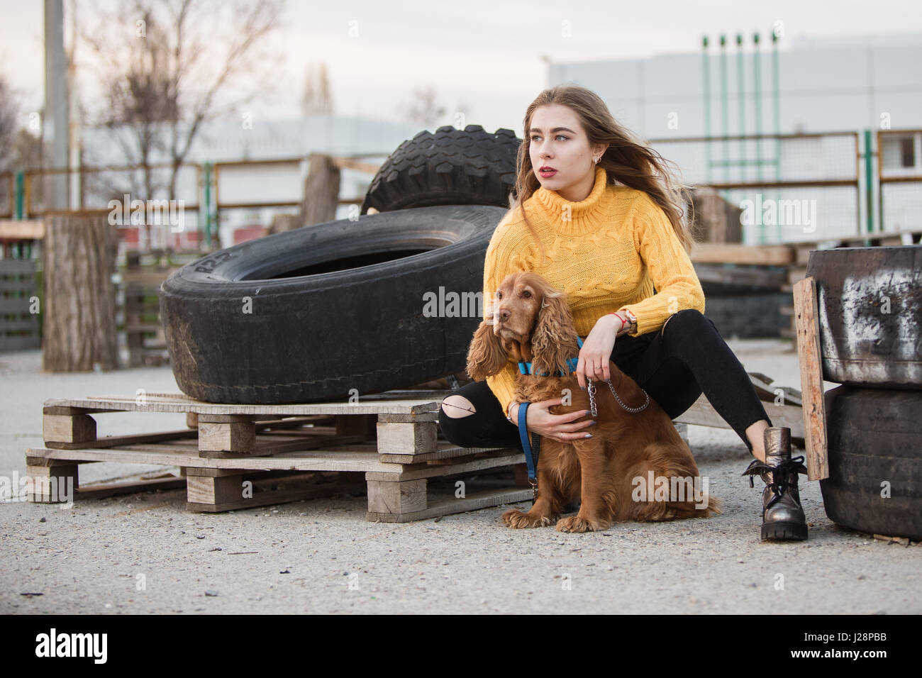 Portrait. Beautiful sexy girl, blond, young woman looking like Jennifer Aniston siting with a dog cocker spaniel, on a background of rubber wheels aba Stock Photo - Alamy Portrait. Beautiful sexy girl, blond, young woman looking like Jennifer Aniston siting with a dog cocker spaniel, on a background of rubber wheels aba Stock Photo - Alamy