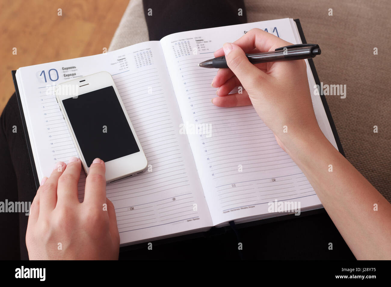 woman writing contact list from mobile phone into her agenda business
