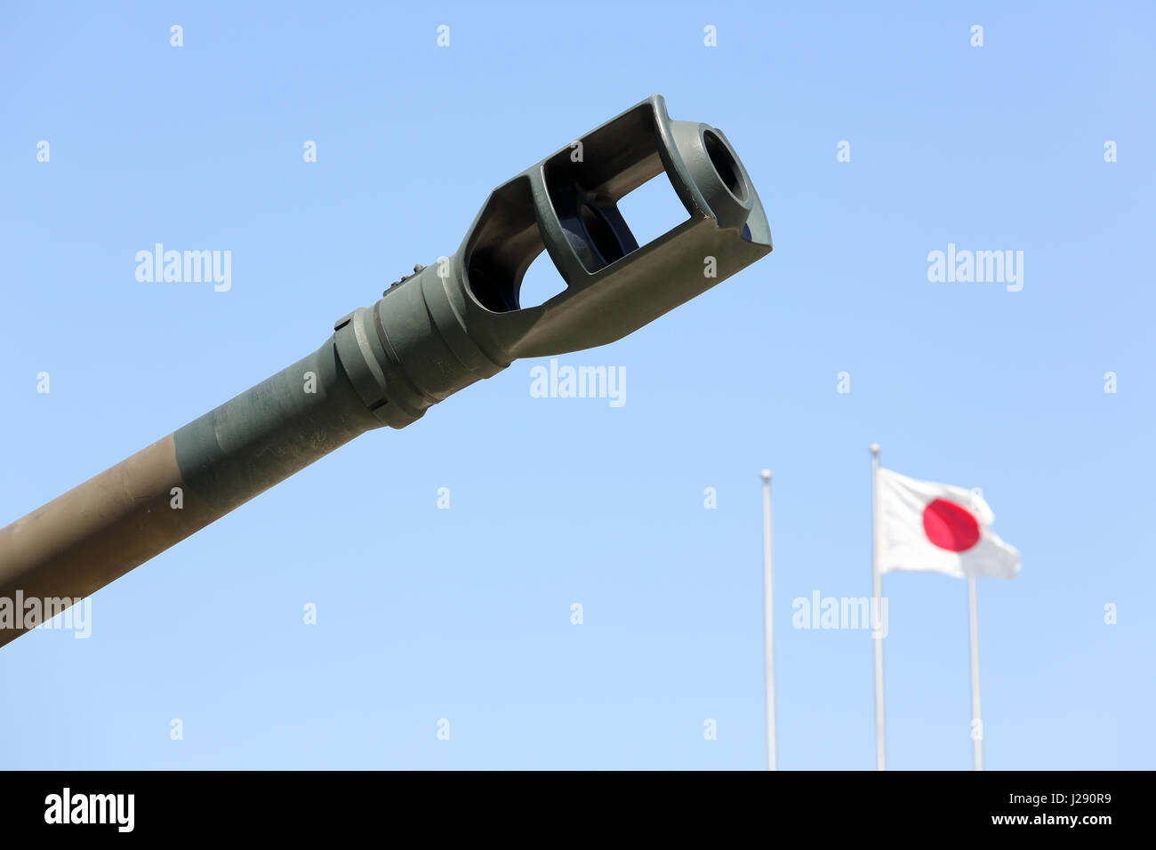 Japanese military cannon with japanese flag against a blue sky Stock Photo