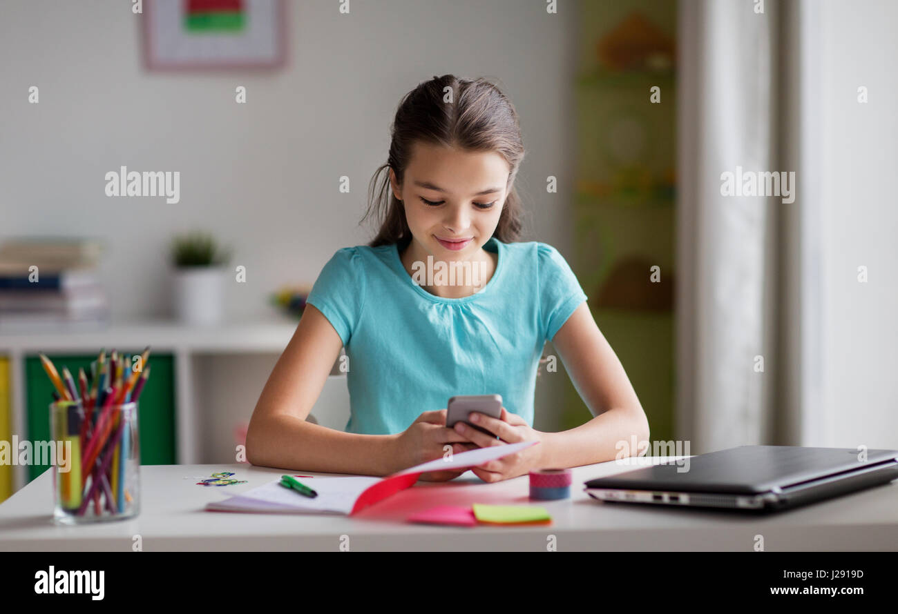 girl with smartphone distracting from homework Stock Photo