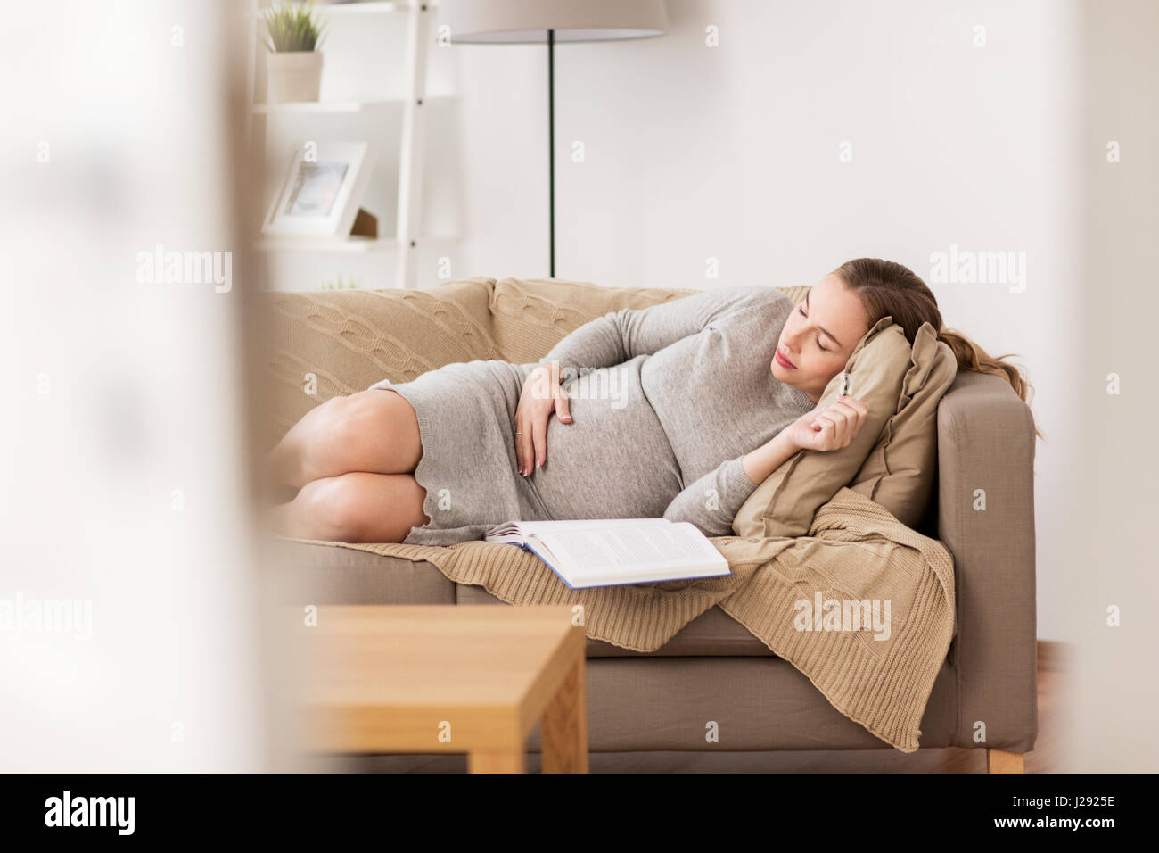 happy pregnant woman sleeping on sofa at home Stock Photo