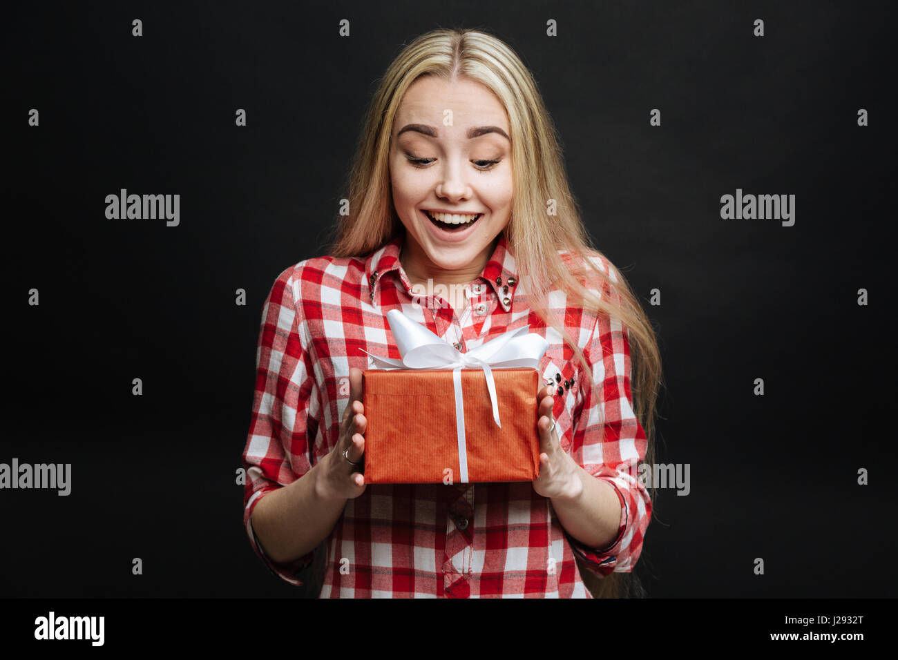 Touched girl getting gift box in the black colored studio Stock Photo