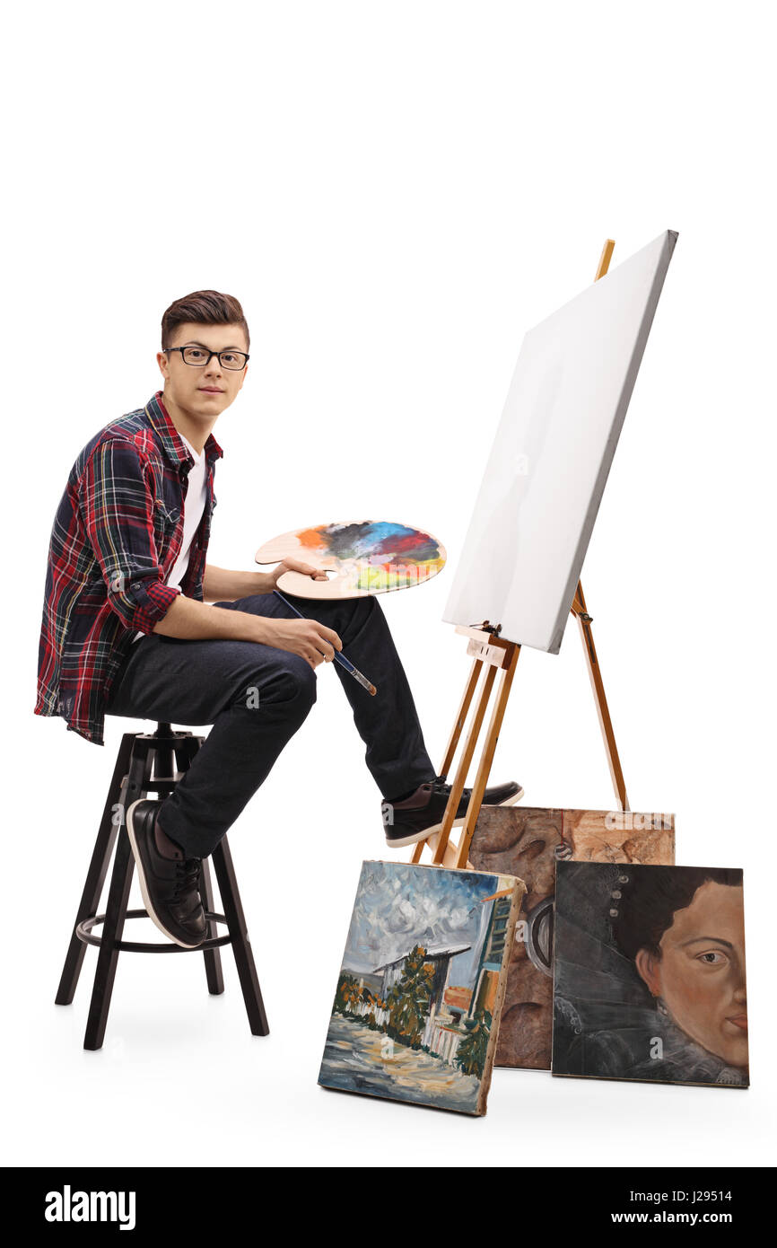 Teenage painter sitting in front of a blank canvas and looking at the camera isolated on white background Stock Photo