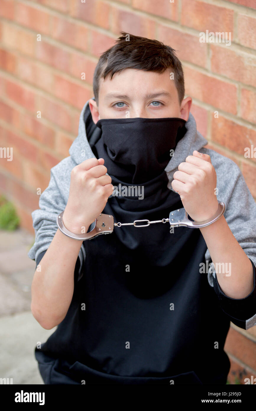 Young caucasian teenage boy in handcuffs after being arrested Stock Photo