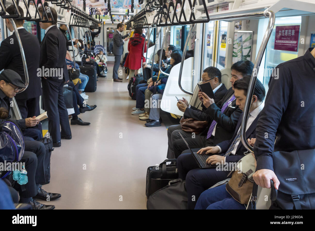 Tokio, Japan - April 8th, 2017: Passengers reading, using laptop and tablets, onboard a japanese train on the way to Tokio Station. Stock Photo