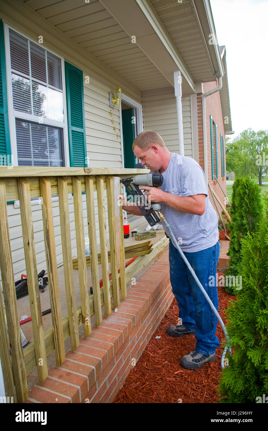 Carpenter is adding rails to porch on front of house, will add value for resale Stock Photo