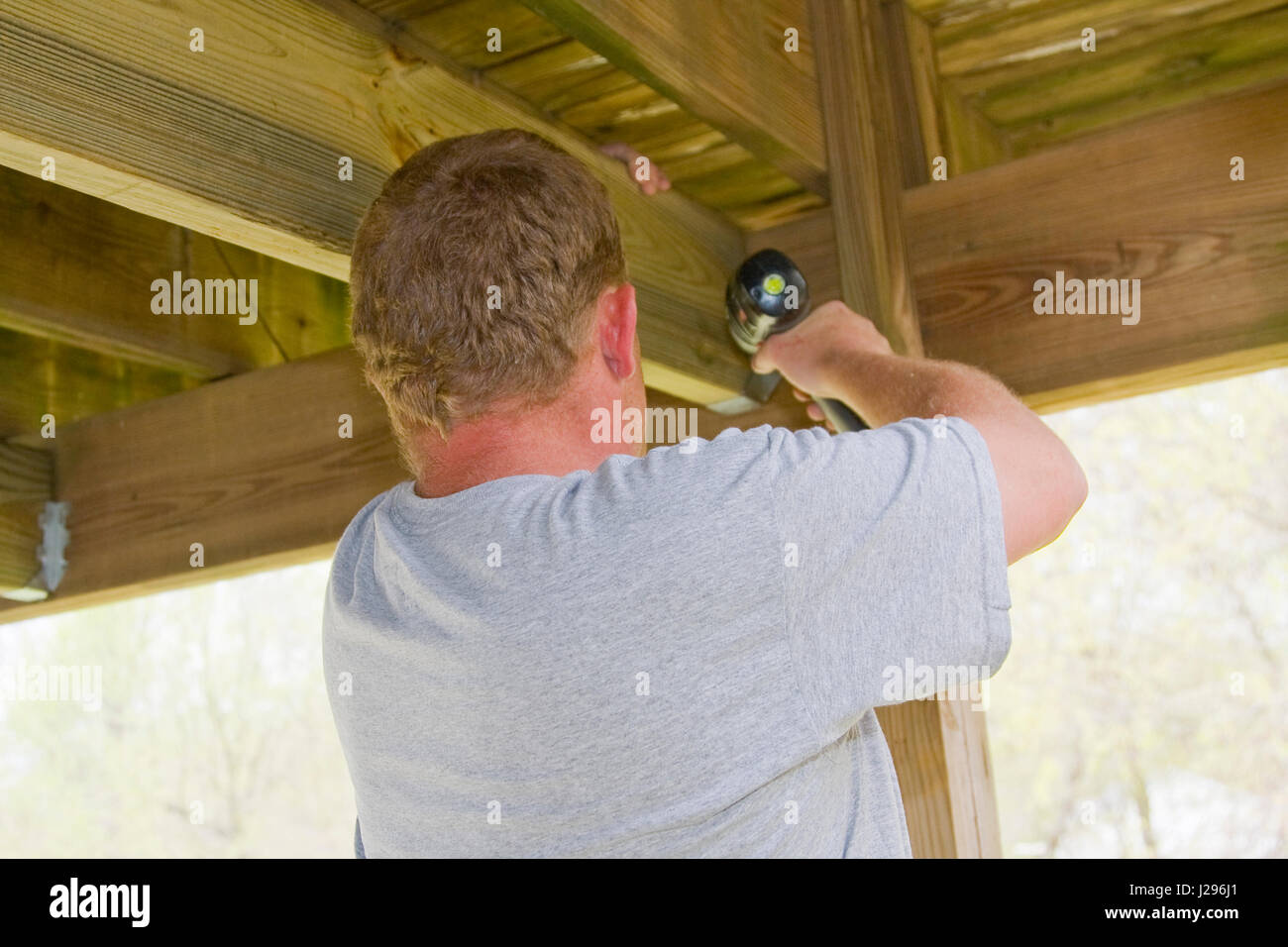 Carpenter is adding steel braces to underneath of deck,Deck will be much stronger able to hold more weight Stock Photo