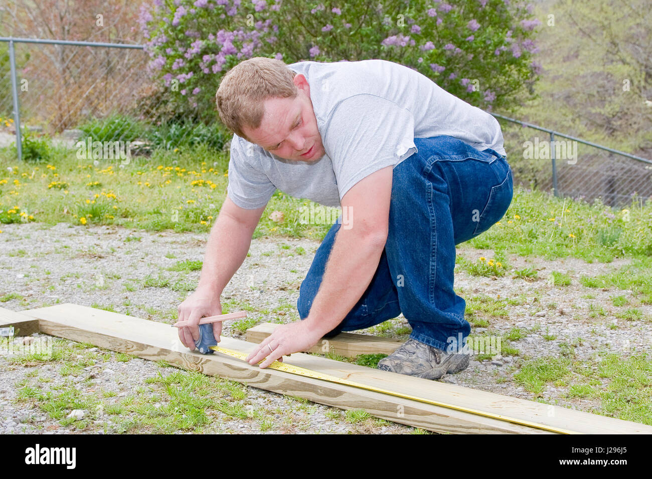 Carpenter using tape measure to set mark on a 2 x 8 board that will be used on deck framing Stock Photo