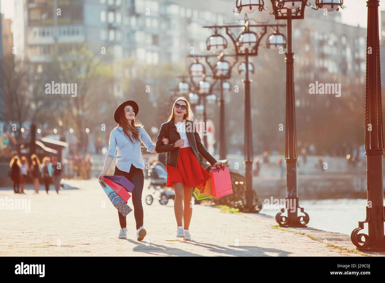 Two girls walking with shopping on city streets Stock Photo - Alamy