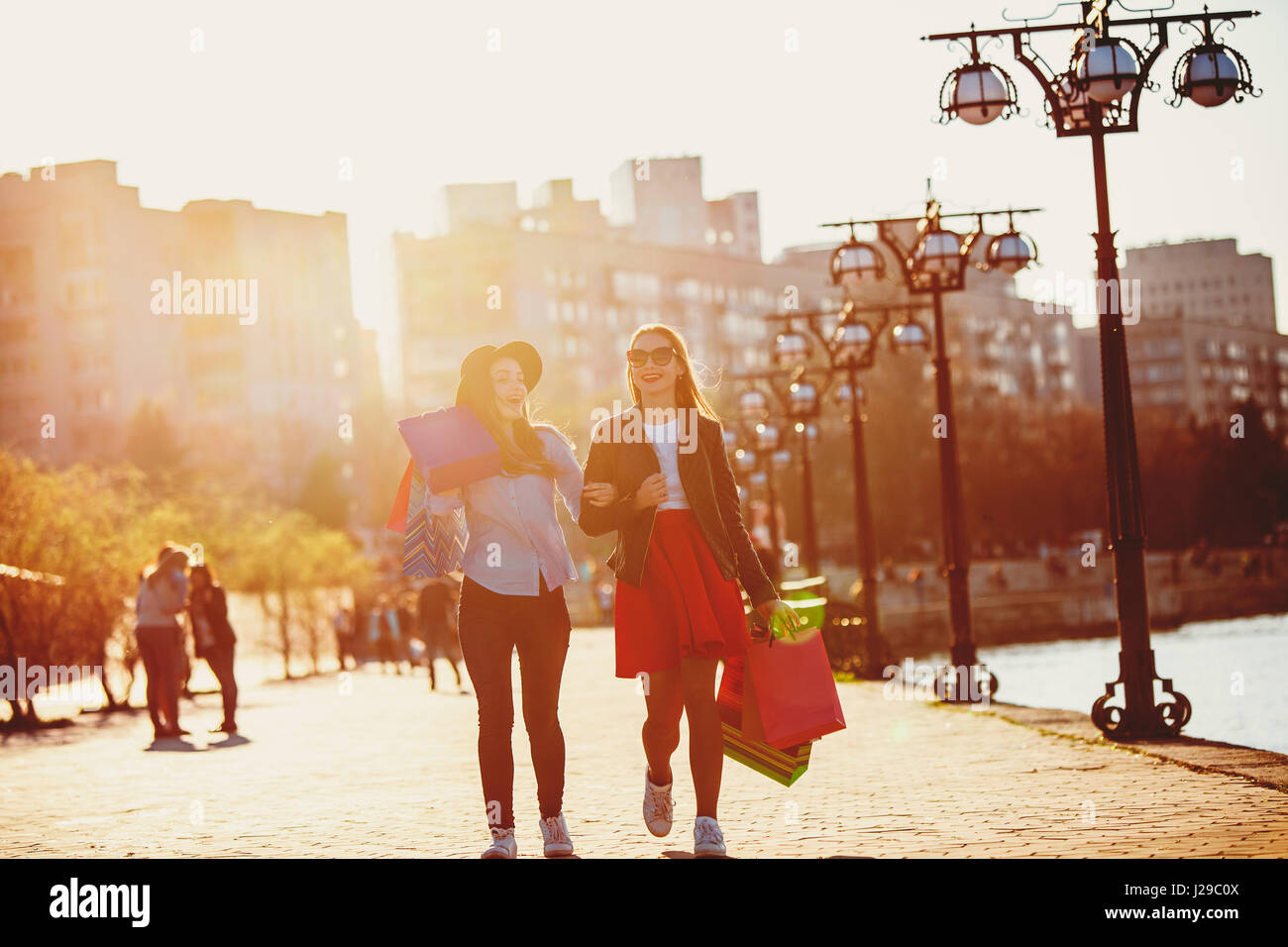Two girls walking with shopping on city streets Stock Photo - Alamy