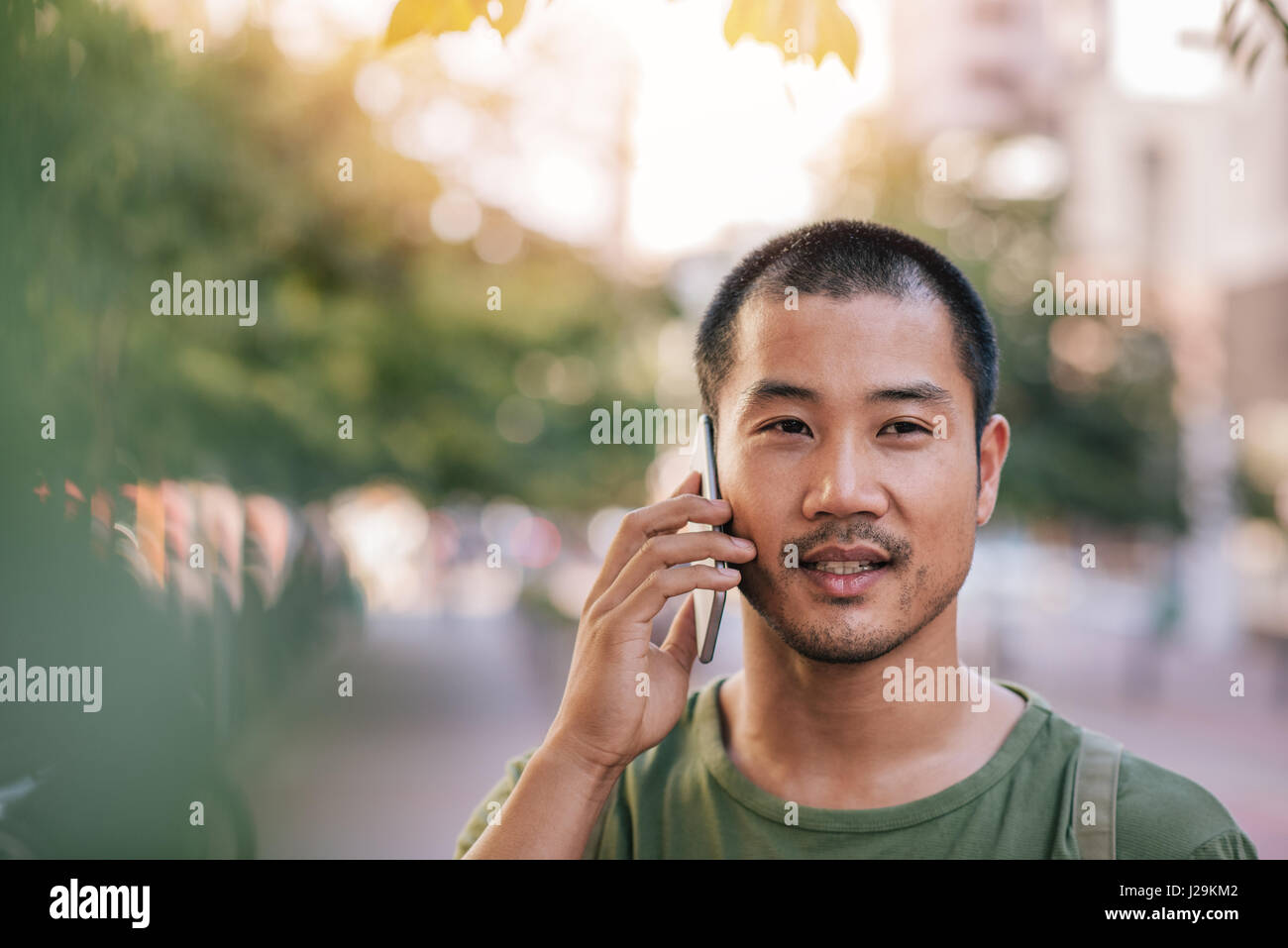 Young Asian man talking on his cellphone outside Stock Photo