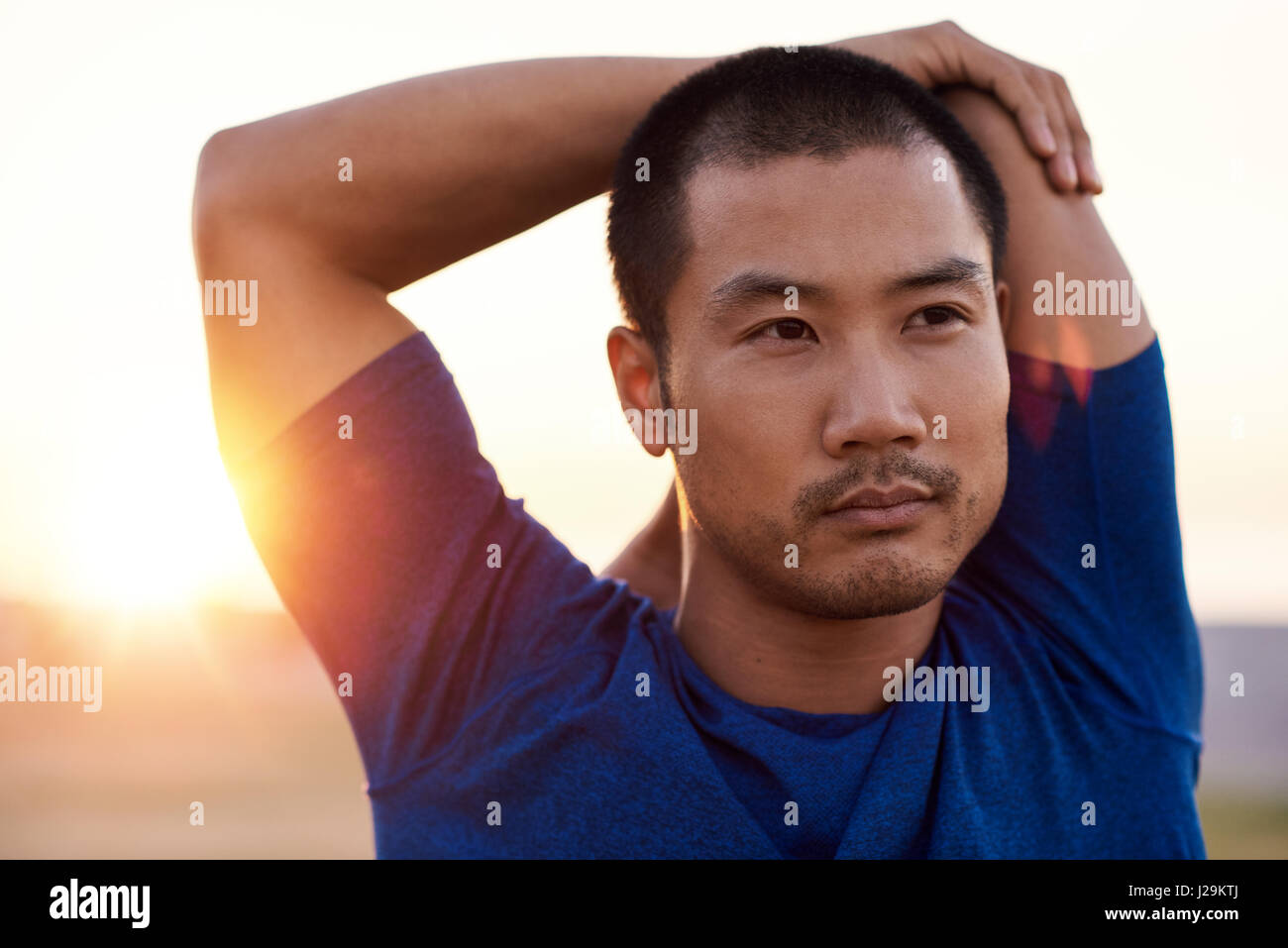Focused young Asian man stretching his shoulders before a run Stock Photo