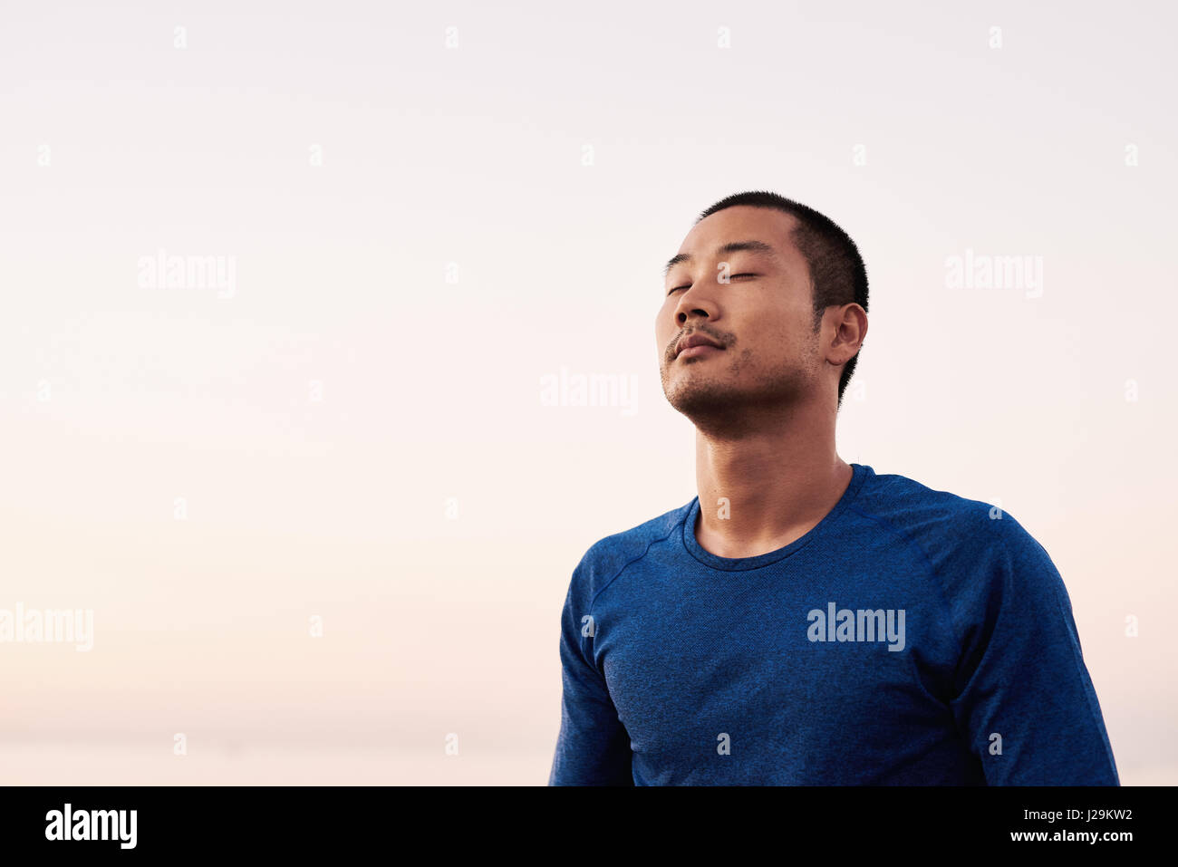 Young Asian man enjoying a break from a morning run Stock Photo