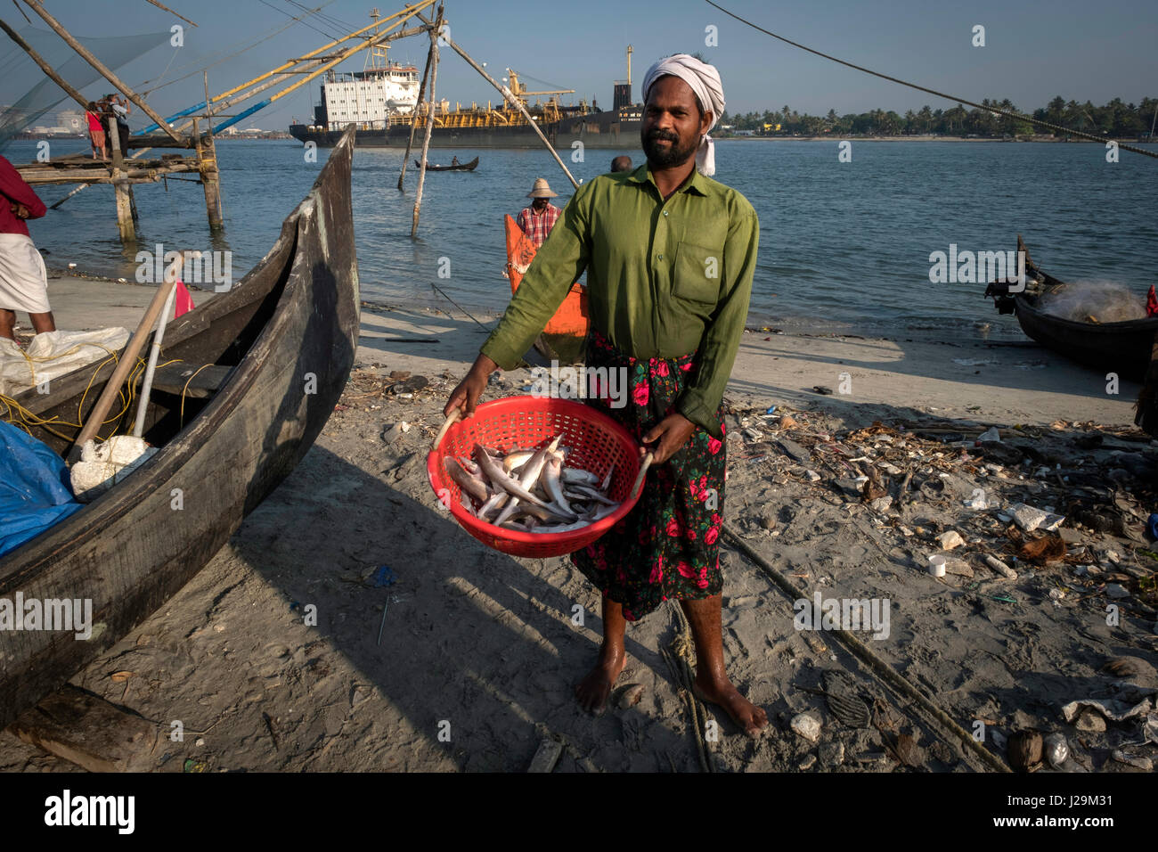 A fisherman shows a basket full of fish that transports to be sold in the market. Stock Photo