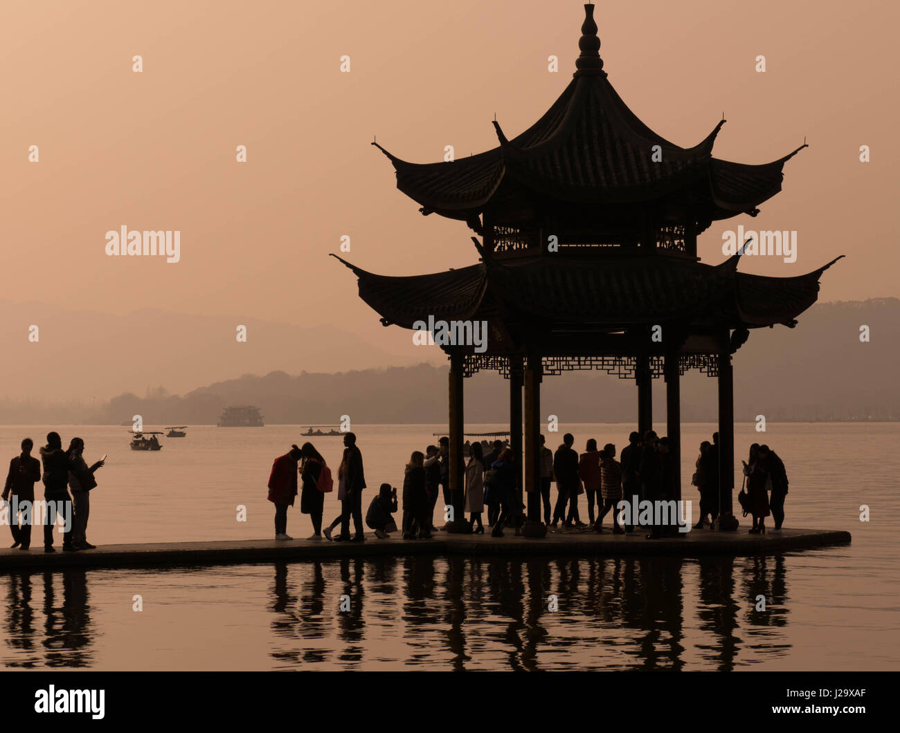 Visitors standing in silhouette on West Lake pagoda in Hangzhou, China Stock Photo