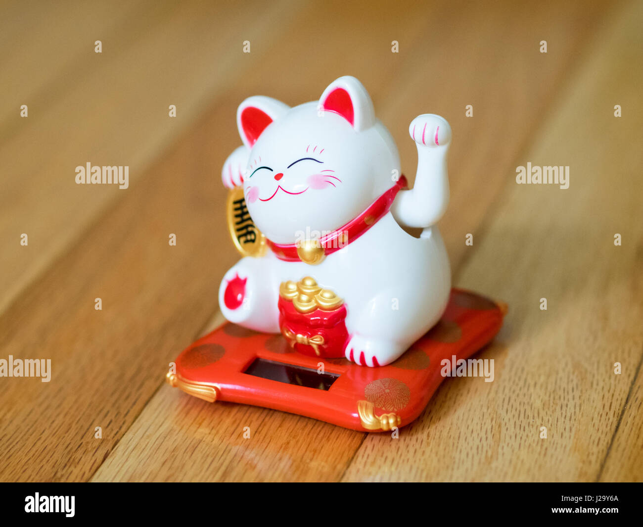 A maneki-neko (literally, "beckoning cat" in Japanese, also known as a lucky cat, Chinese lucky cat, or happy cat) figurine. A popular lucky charm. Stock Photo