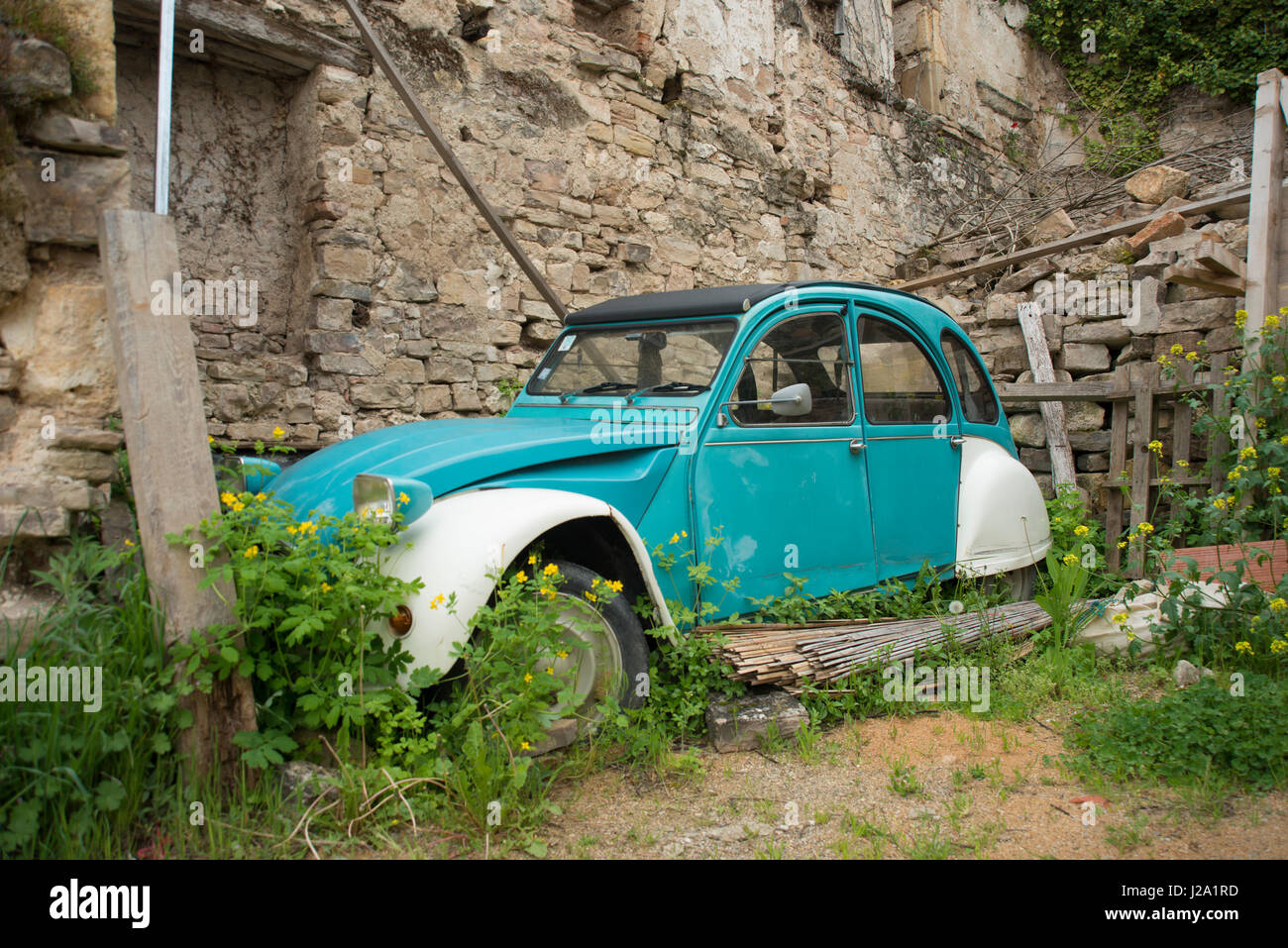 An old CitroÃ«n 2CV, stowed away near the ruins of a house in a French town Stock Photo