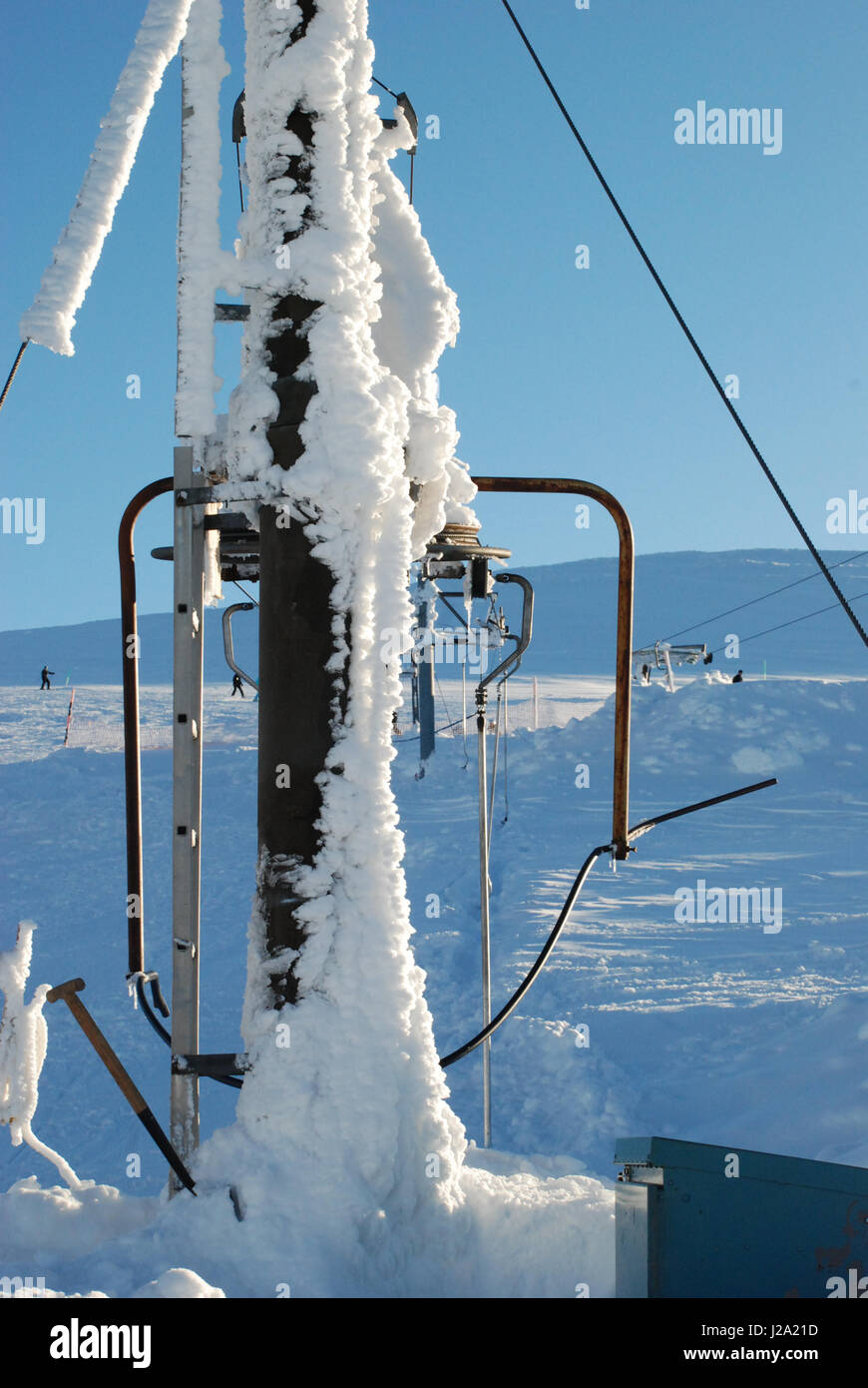 Wind-driven snow cakes a ski tow pylon on Cairngorm. File Photo. Stock Photo
