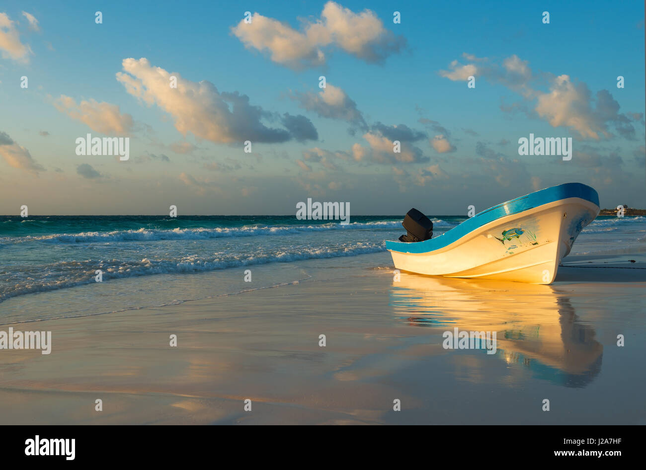 Typical fishing boat on the beach of Tulum at sunset by the Caribbean Coast of Mexico. Stock Photo