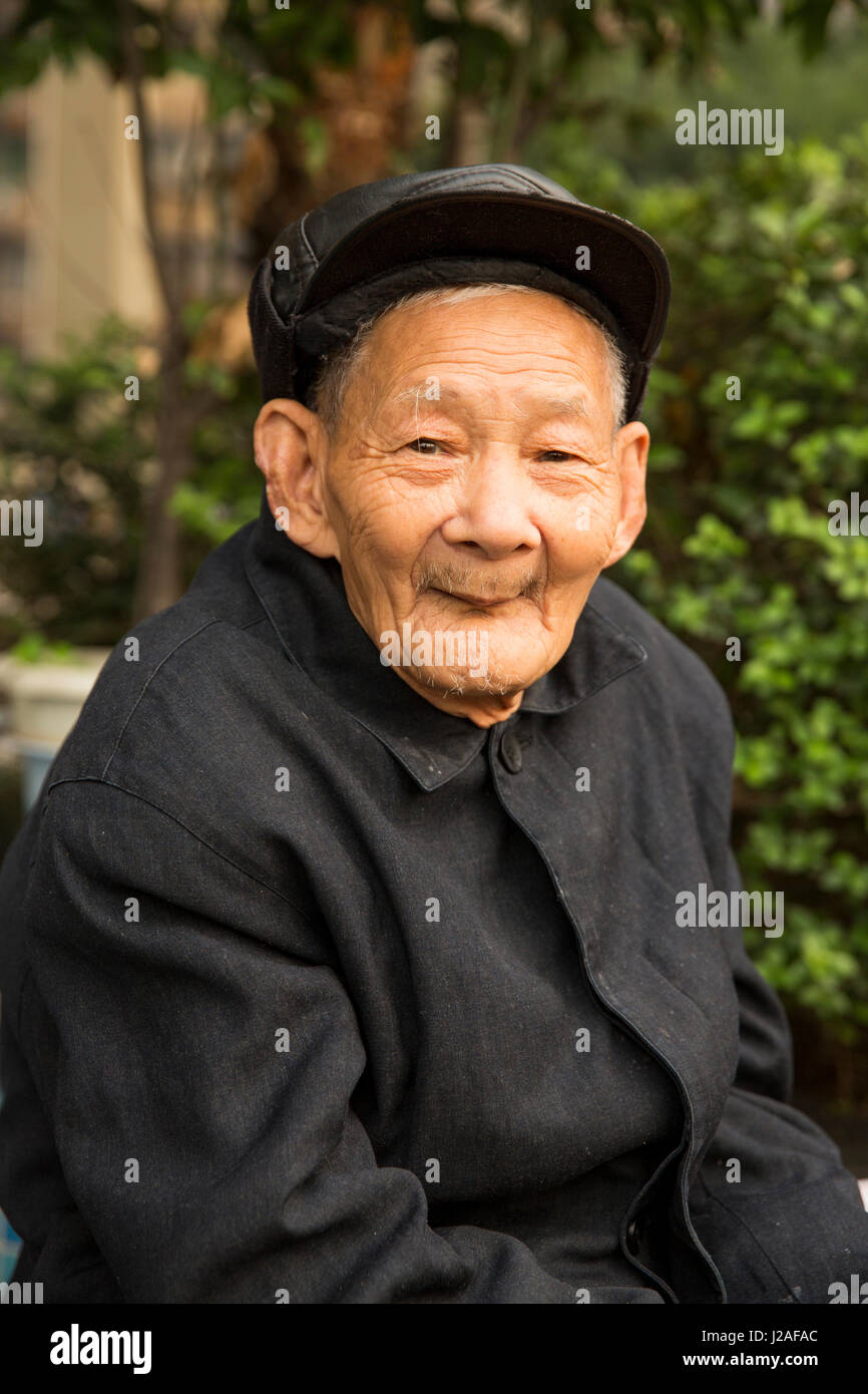 China, Chongqing, Portrait of elderly man sitting in city park overlooking Yangzi River on autumn afternoon Stock Photo