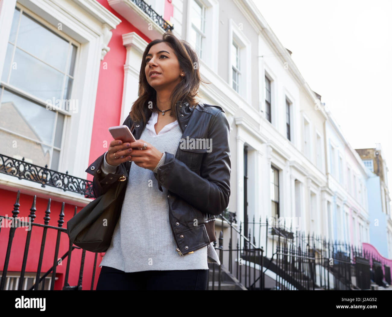 Low angle view of a young woman using mobile phone in street Stock Photo