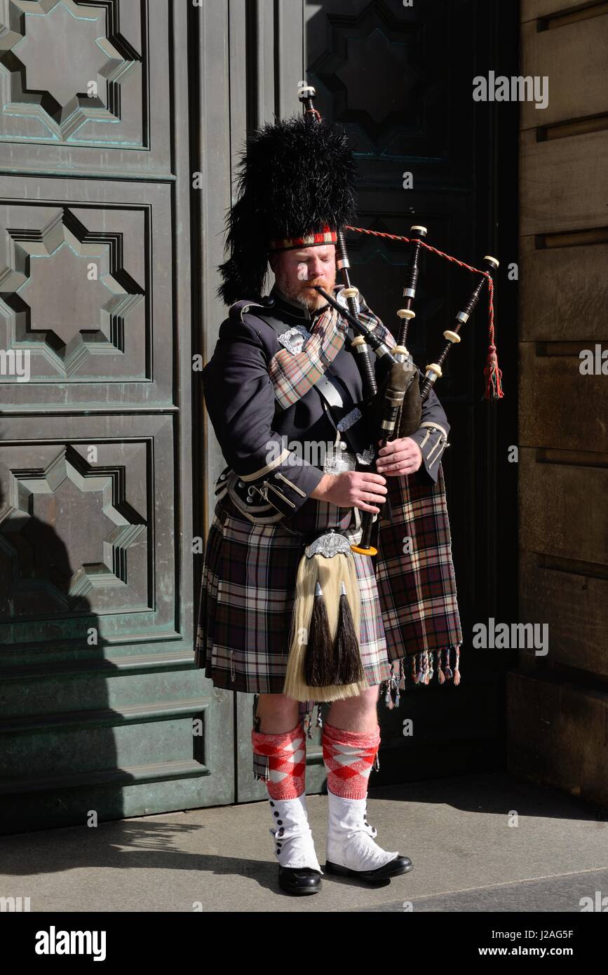 A lone piper in full Scottish regalia busks on the Royal Mile, Edinburgh, Scotland, UK Stock Photo