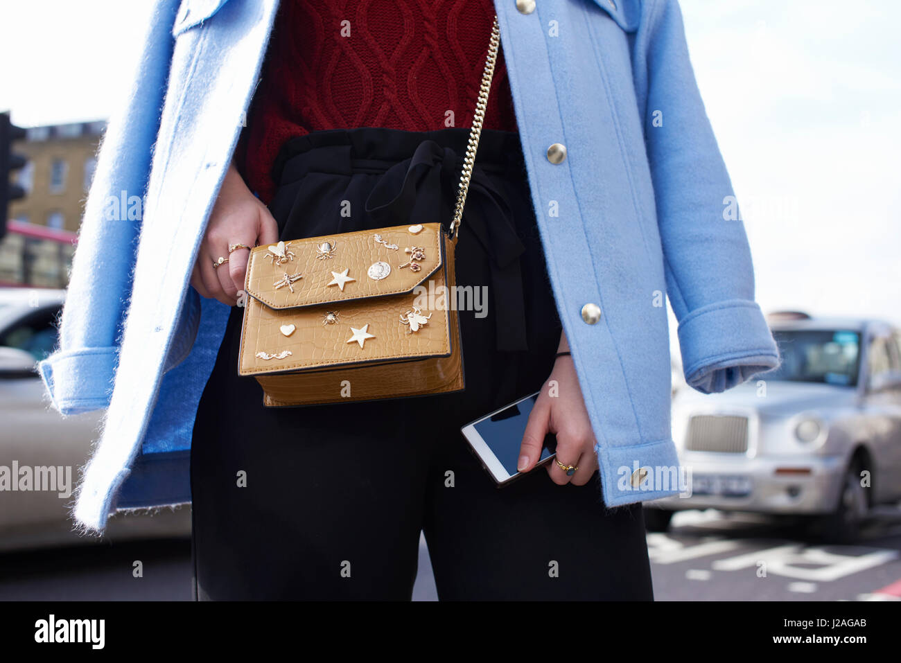 LONDON - FEBRUARY, 2017: Mid section of woman wearing Zara cross body handbag with metal details and blue coat on shoulders in street during London Fashion Week Stock Photo