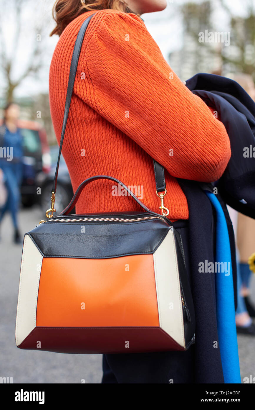 LONDON - FEBRUARY, 2017: Mid section of woman wearing orange sweater and a four  colour leather panel Mulberry shoulder bag in the street during London Fashion Week, vertical Stock Photo
