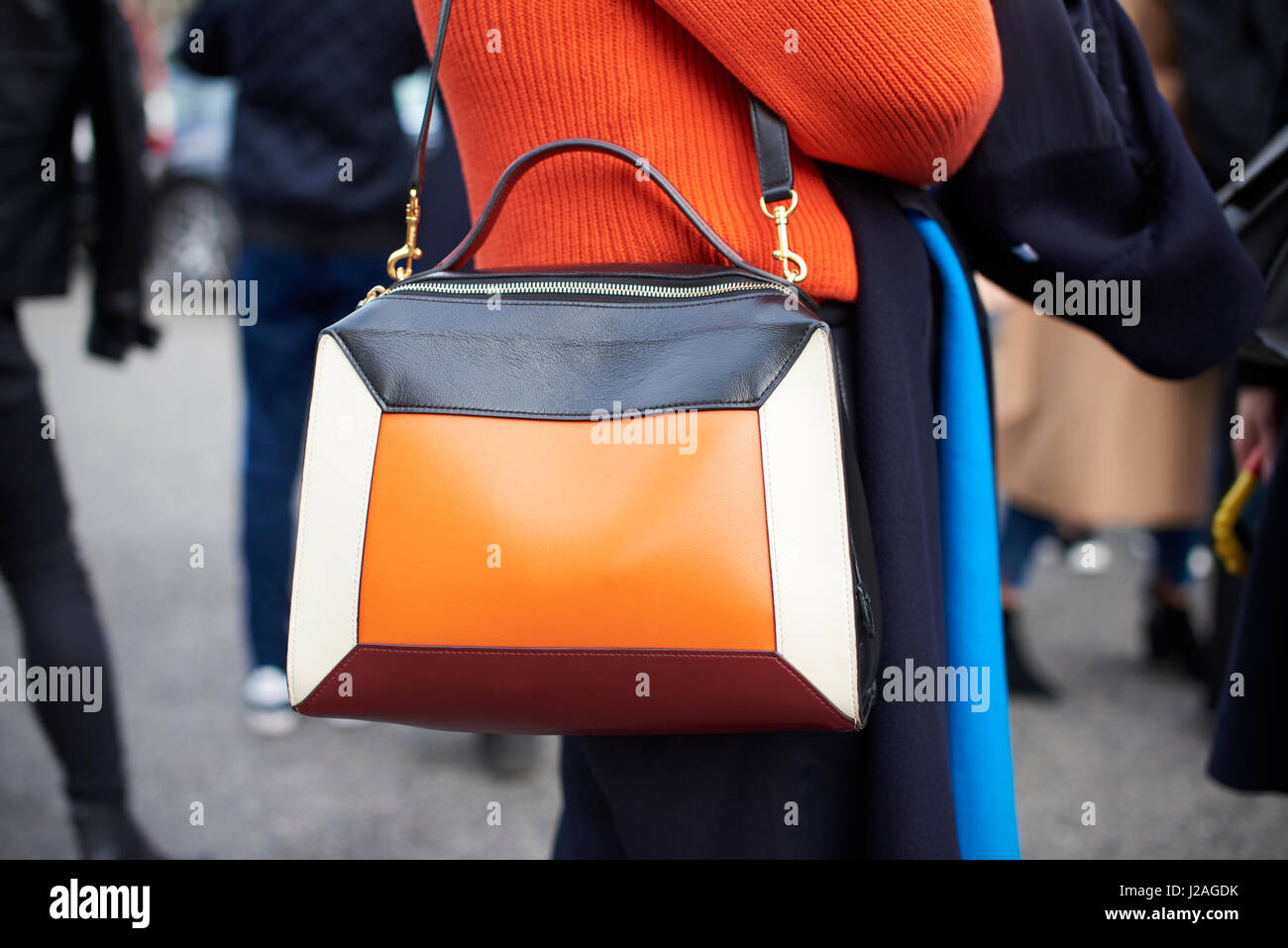 LONDON - FEBRUARY, 2017: Mid section of woman wearing orange sweater and a four  colour leather panel Mulberry shoulder bag in the street during London Fashion Week, horizontal Stock Photo