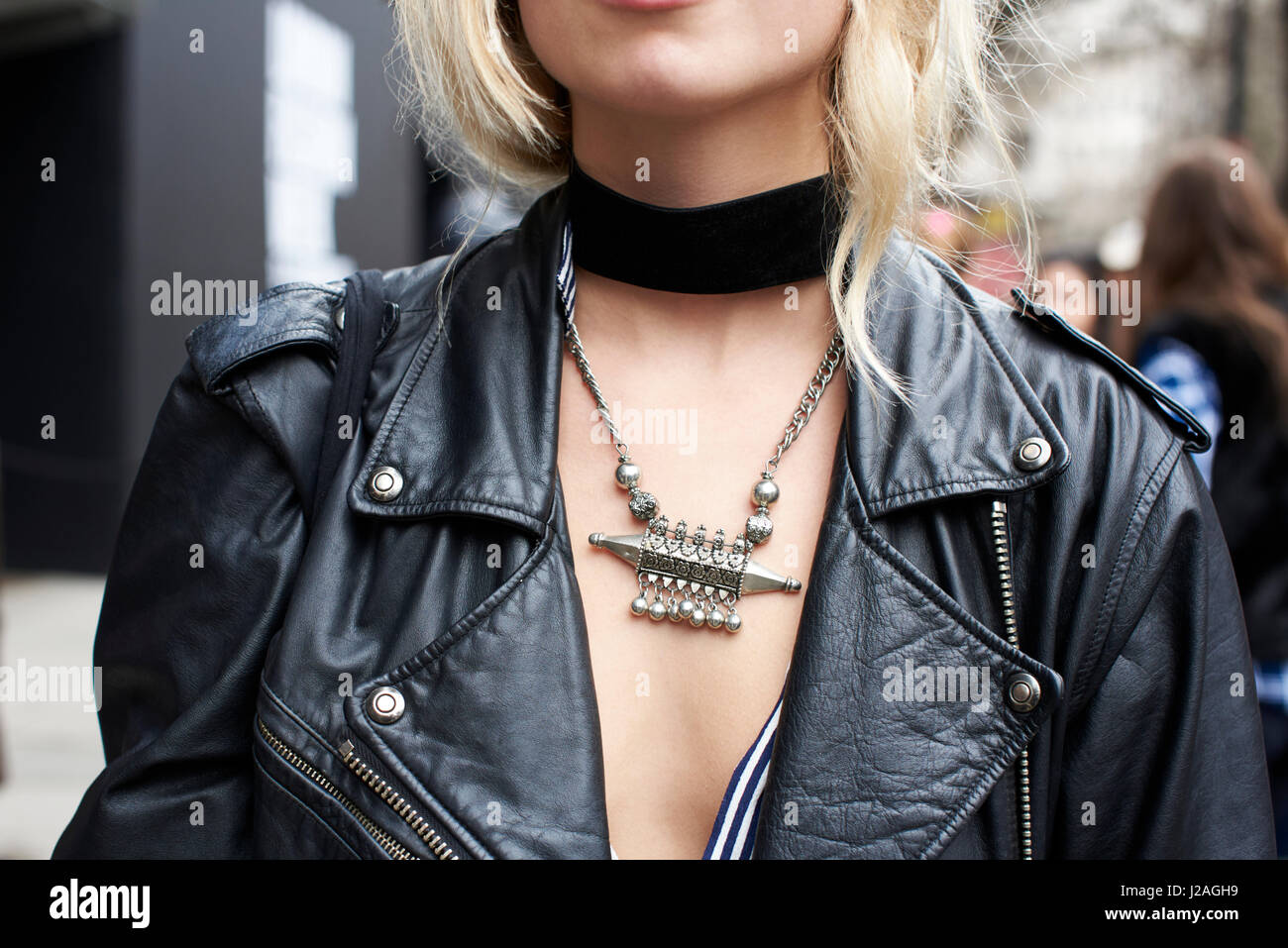 LONDON - FEBRUARY, 2017: Close up crop of  woman wearing a black leather jacket, black choker and a silver tribal necklace in the street during London Fashion Week, horizontal, front view Stock Photo