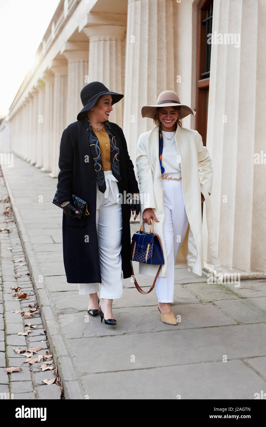 LONDON - FEBRUARY, 2017: Full length view of two fashionable women wearing coats and hats walking in street, London Fashion Week, day four. Stock Photo