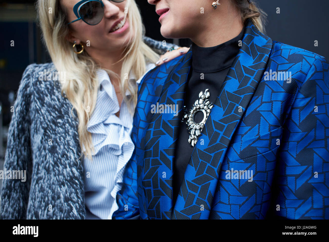 LONDON - FEBRUARY, 2017: Mid section close up of two fashionable women, one wearing a wool jacket and the other a patterned silk jacket, London Fashion Week, day five. Stock Photo