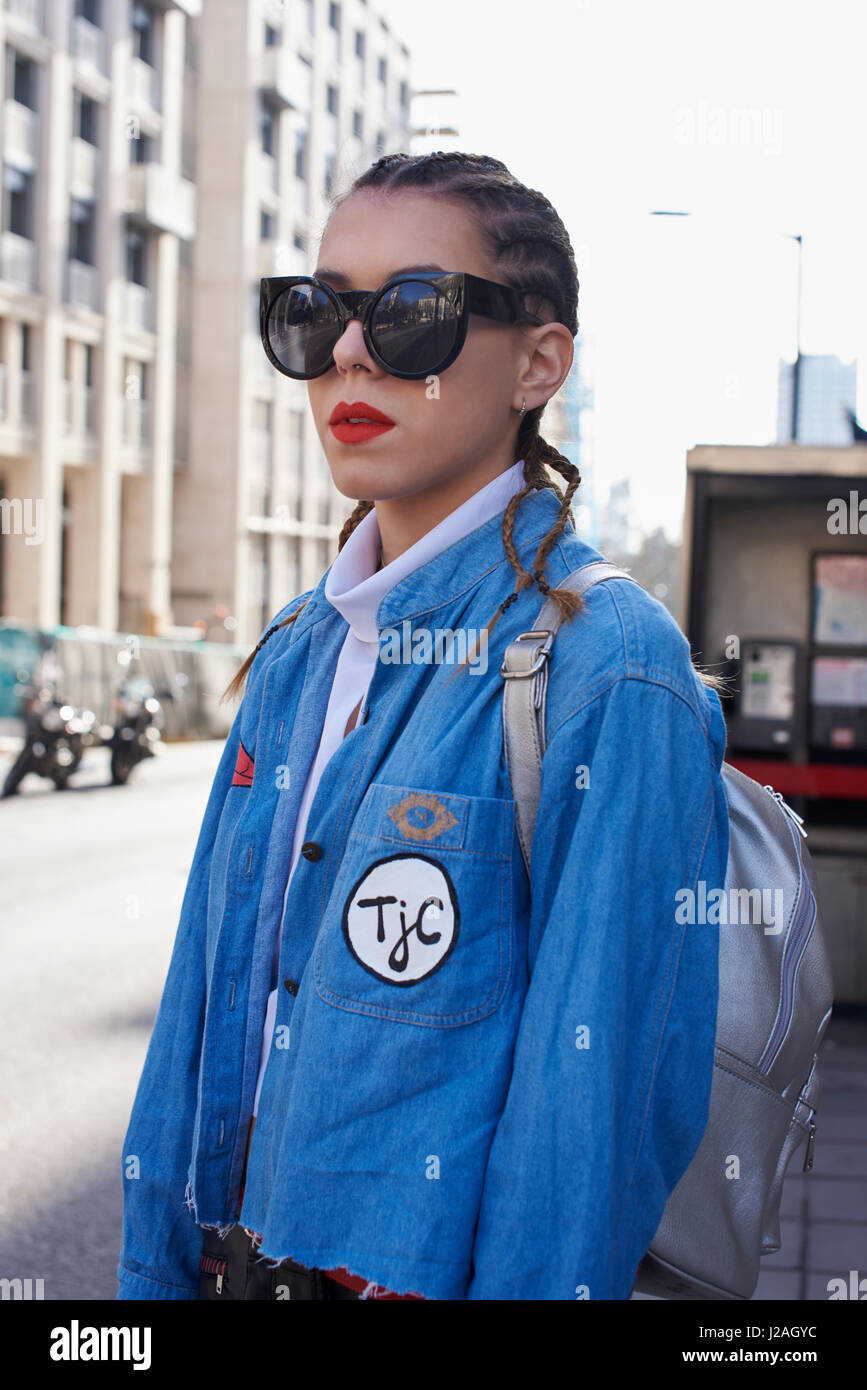 LONDON - FEBRUARY, 2017: Waist up portrait of woman with corn rows hairstyle wearing large sunglasses in the street, London Fashion Week, day four. Stock Photo