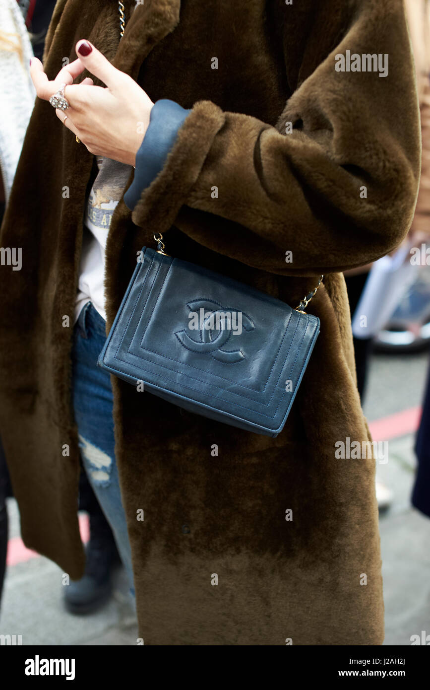 LONDON - FEBRUARY, 2017: Mid section of woman wearing a brown fur coat with a cross body Chanel handbag in the street during London Fashion Week, vertical Stock Photo