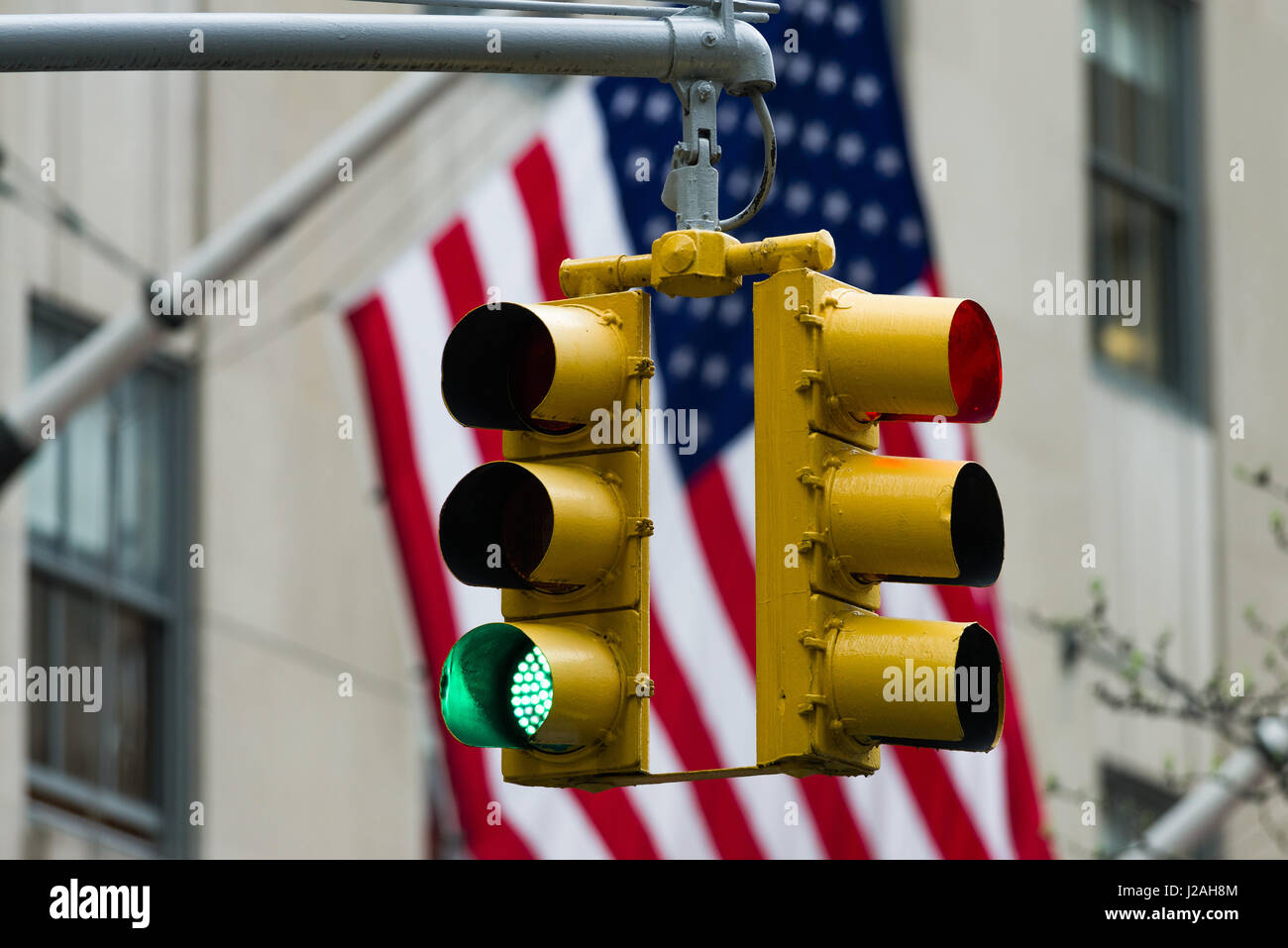 Green Traffic Light In Front Of American Flag, Immigration, Travel and Net Neutrality Restriction Concept Stock Photo