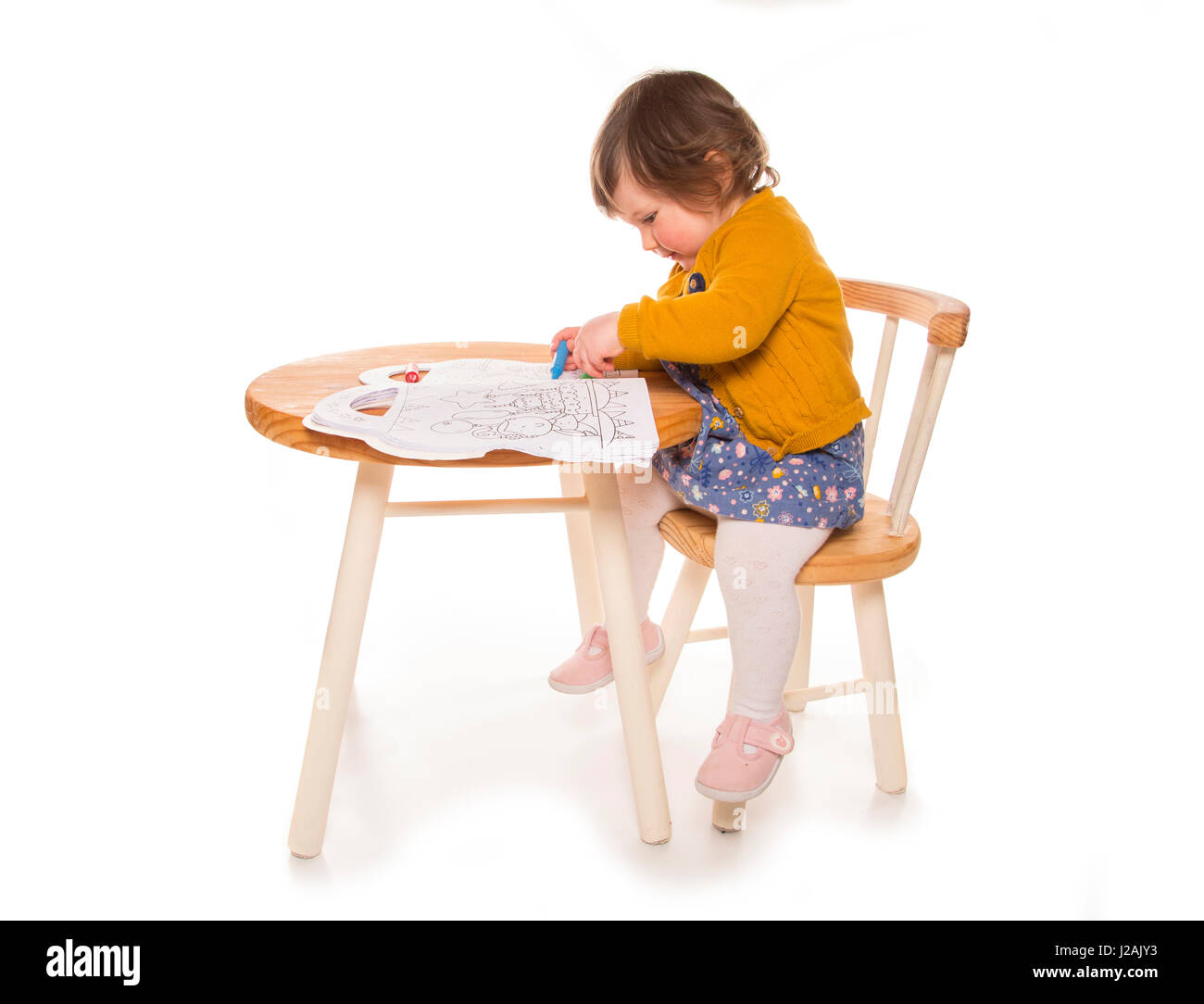 toddler at table colouring with crayon Stock Photo