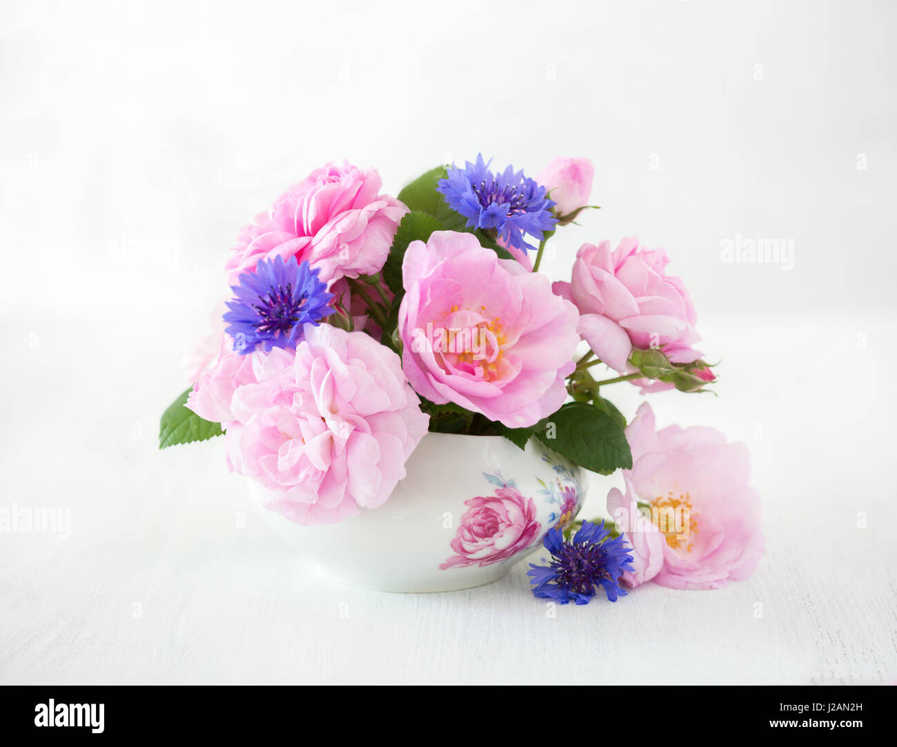 Colorful bouquet of light pink roses and cornflowers on pale  grey  background. Stock Photo