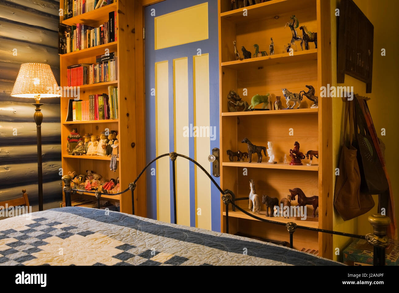 Partial view of the bed and pinewood bookcases in the guest bedroom inside a country cottage style residential log home Stock Photo