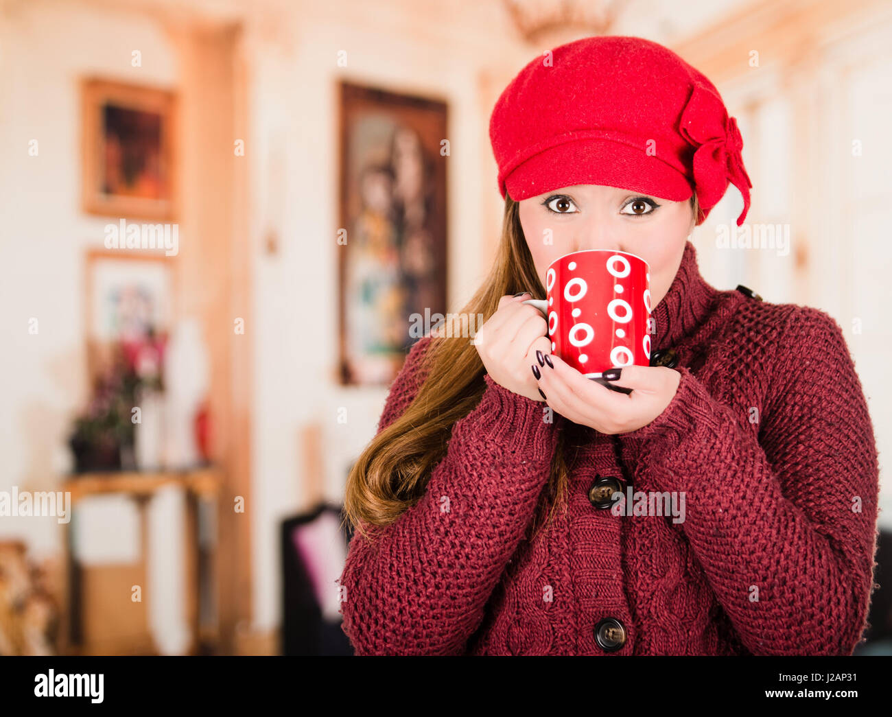 Pretty young brunette woman wearing red sweater and beenie, taking a ...
