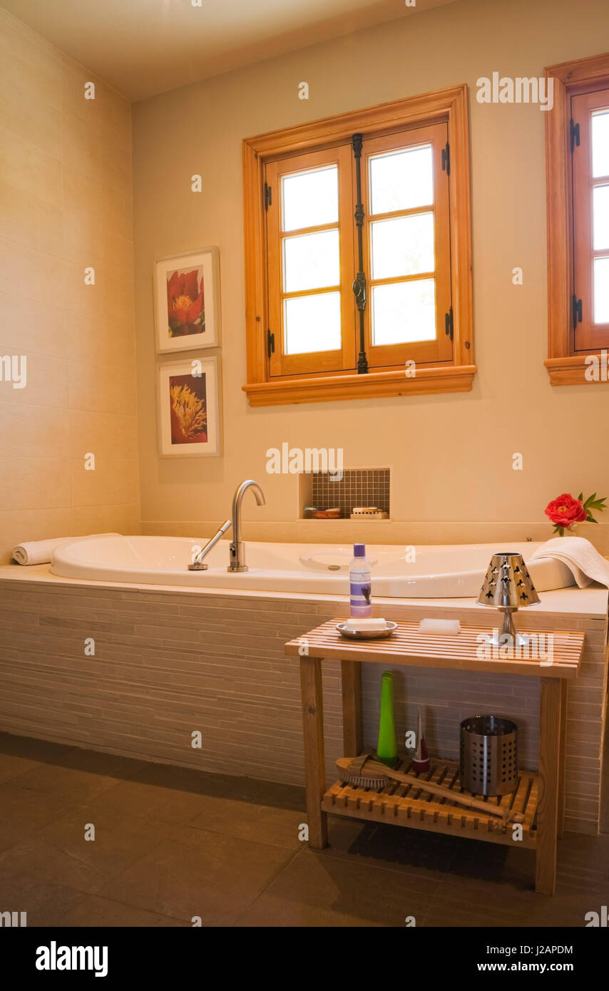 Bathtub and small wooden table in the main bathroom inside a stacked