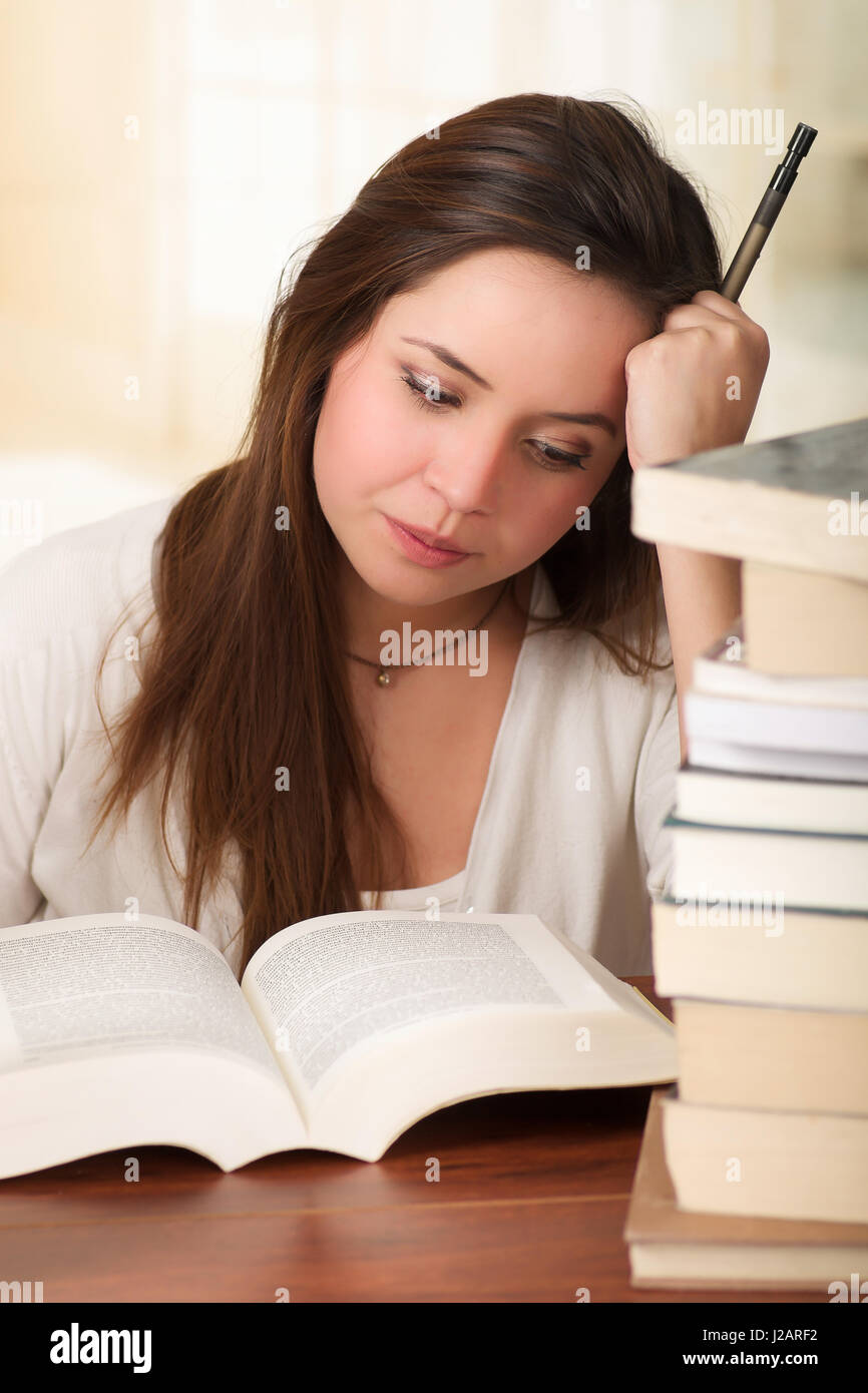 tired student girl falling asleep reading a book in the library Stock