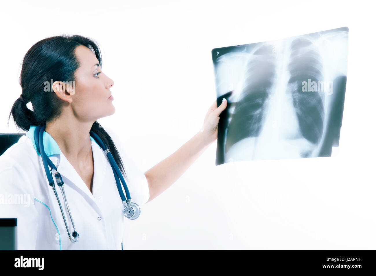 Young female doctor looking at the x-ray picture of lungs in hospital. Health care and prevention concept. Toned image Stock Photo