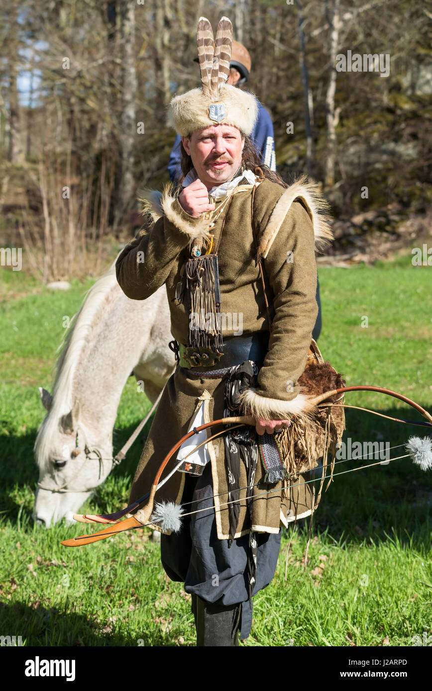 Brakne Hoby, Sweden - April 22, 2017: Documentary of small public farmers day. Cosplay archer in well made costume. Horse and rider in background. Stock Photo