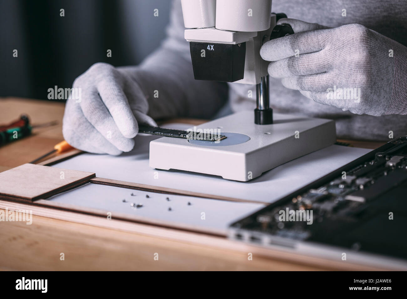 Detail image of technician examining random access memory with microscope at electronics store Stock Photo