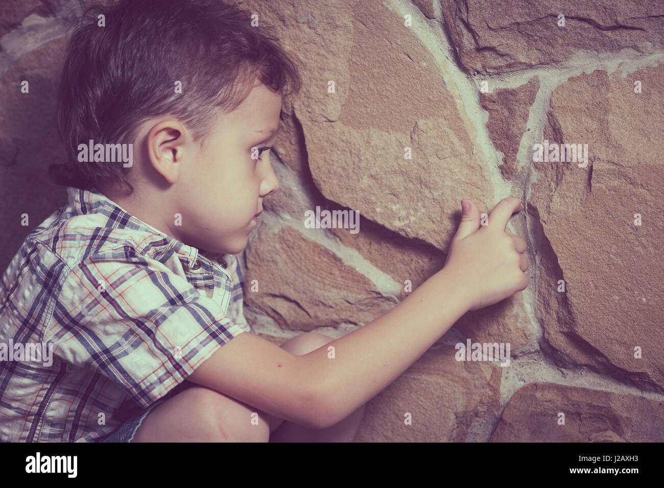 sad little boy sitting near the wall at the day time Stock Photo Alamy