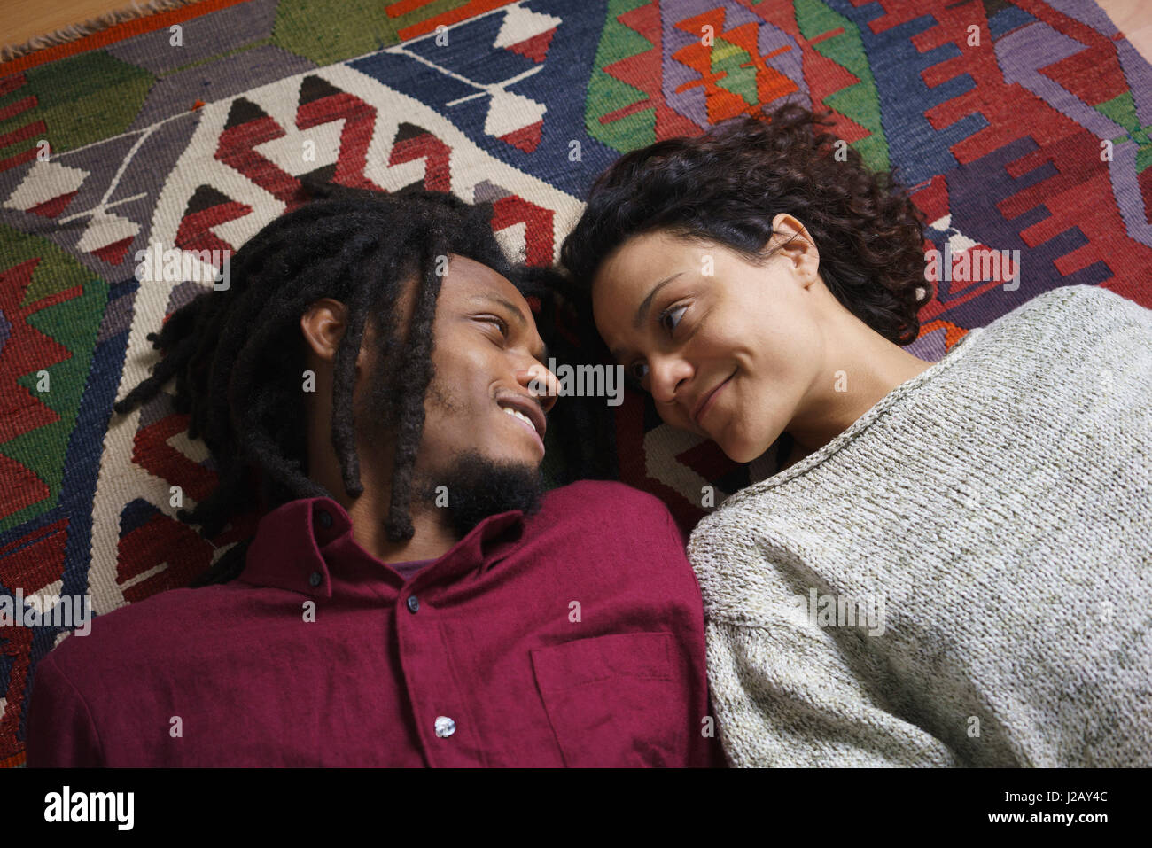 High angle view of affectionate couple looking at each other while lying on carpet Stock Photo